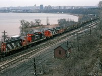 Powered by 3 GP9's, a train of mostly scrap metal loads in gondolas is climbing the grade from Hamilton Stuart St Yard, timetable eastbound on CN's Oakville Sub (compass north). It looks like traffic for Lake Erie Steel at Nanticoke, in which case it will switch onto to the "Cowpath" just ahead to head west on the Dundas Sub. <br><br>Note there are cabooses at both ends of the train, and middle loco CN 4514 has fabricated winterization covers, suitable for snowplow service.